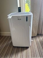 Front view of DeLonghi Pinguino portable AC with digital control panel and remote control on top