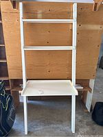 Front view of white wooden leaning planter shelf showing three shelves and clean white paint.