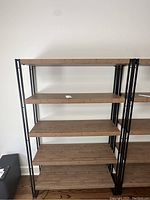 Front view of the shelving unit showing five wooden shelves and black metal frame.