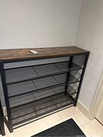 Front view of fully assembled shoe rack showing four mesh shelves and wood-effect top
