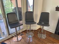 Three stools lined up in front of sliding glass door, showing overall appearance and matching set