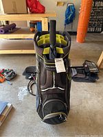 Front view showing top club dividers with yellow lining, umbrella handle, front zippered compartments, and Sun Mountain logo