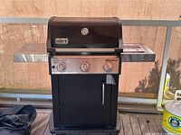 Front view of grill with lid closed, control panel and side shelves visible
