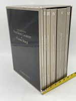 Black cardboard slipcase with silver foil 'Collection Yves Saint Laurent et Pierre Bergé' and 'Christie's' text, houses six taupe volumes