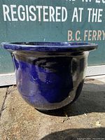 Side view of large blue glazed ceramic flower pot showing color and shape.