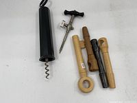 Full view of the lot showing six corkscrews of various types and materials arranged on white surface.