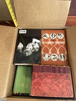 Four hardcover books in corrugated box: black photobook, orange "Intramural Programs", green cloth volume, red marbled boards/blue spine volume