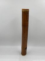 Full view of bamboo rainmaker showing natural wood and decorative wrapping at top.