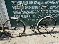 Side view of vintage Raleigh bicycle showing full frame, wheels, saddle, handlebars, and chain guard.