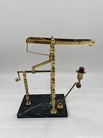 Front view of vintage brass wine bottle opener with black marble base, crank handle, and lever arm with red cork holder
