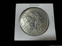 Obverse of 1880 Morgan Dollar in cardboard 2x2 holder on black background