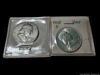 Two Ben Franklin half dollar coins in plastic holders; the 1948 coin with D mint mark is noted on paper inside the holder along with the word 'Half'.