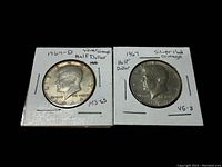 Two Kennedy Half Dollar coins in white cardboard holders showing obverse sides with labeling for 1964-D and 1967 coins, silver content, and condition grades.