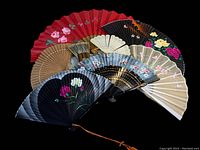 Top-down photo of all 8 vintage fans fanned out showing variety of designs and colors, floral patterns visible