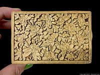 Close-up of the box lid showing detailed deep relief floral and leaf carvings in yellow cinnabar lacquer.