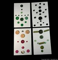 Four white cards each holding an assortment of vintage buttons in different colors and sizes, mostly Bakelite.
