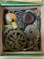 Top down view of metal findings and fixtures in a cigar box, showing various decorative and functional hardware items including cast pieces, wood and ceramic parts.