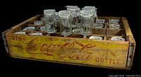 Side view of wooden Coca Cola crate showing faded logo and compartments for spice jars.