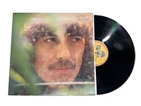 Close-up photo of George Harrison vinyl record partially pulled from original album cover sleeve with a clear view of the iconic album artwork featuring George Harrison's face.