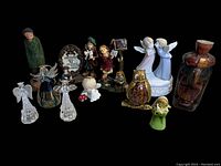Lot of 11 small miscellaneous figures against a black background showing various materials and styles including glass, ceramic, wood, and painted figures.
