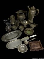 Arranged vintage metalware pieces on black background showing shapes and finishes