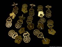 Set of 13 vintage brass/bronze Chinese style drawer pulls laid out on black background showing front and back sides with screws attached.