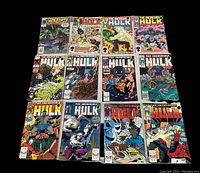 Photo showing 12 Hulk comic books with various cover art and issue numbers visible, arranged in a grid on black background.