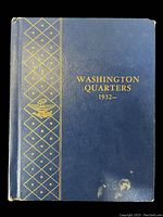 Front cover of blue coin album with gold “Washington Quarters 1932–” text, showing wear and scuffs