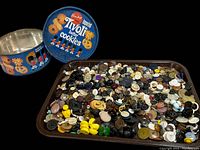 Buttons inside a brown metal tray and vintage Tivoli butter cookies tin lid and container.