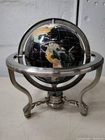 Front view of the vintage globe on a decorative metal stand showing North America and the circular metal frame.