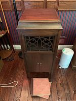 Front view of closed wooden cabinet with decorative metal grille above double doors.