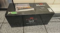 Front view of the Kuuma Stow N Go 160 grill box showing product image and branding.