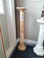 Full view of the stone pedestal standing in a corner showing its height and color pattern.