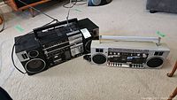 Both boomboxes side by side on carpeted floor