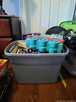 Large gray plastic bin filled with toys, showing colorful Thomas train parts visible on top.