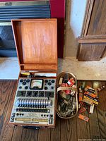 Wooden case open showing Precision Tube Master tester and metal container with vacuum tubes and accessories