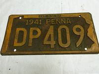 Front view of the 1941 Pennsylvania license plate showing the number DP 409 and expiration date 3-31-42 on the yellow-on-brown background with wear and rust spots.