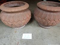 Front side view of two terra cotta pots showing scalloped and wavy decorative patterns.