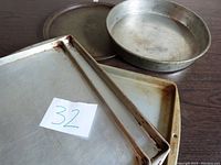 All four baking trays arranged on a dark surface, showing their size comparison and wear.