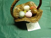 Handmade ceramic basket containing multiple ceramic and glass eggs in various colors