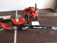 Two chainsaws side-by-side on a table. One is a Homelite 14-inch chainsaw with visible branding.