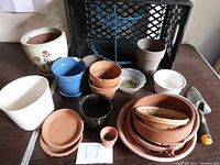 Photo of assorted gardening pots in various materials and a crate in the background