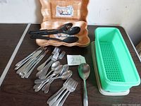 Full view of flatware, plastic serving trays, and wooden trays arranged on table.