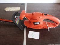 Side view of the Black & Decker electric hedge trimmer showing handle, blade guard, and brand label.