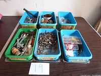 Photo of all six bins on a table labeled with number 19, each container holding assorted tools and hardware items.