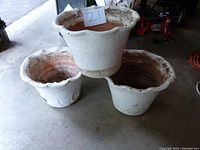 Group of three white painted terracotta pots with scalloped edges and visible paint wear.