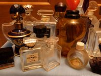 Close grouping of various vintage perfume bottles including Chanel No. 5 with black and gold caps, amber bottle, and others.