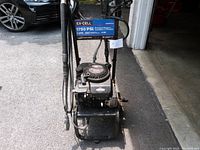 Front angled view of Ex-Cell pressure washer with engine visible, showing attached hoses and wand.