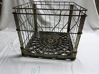Full view of the metal crate showing grid wire sides and solid patterned base.