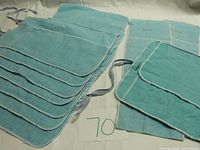 Stack of light blue fabric Tiffany & Co. silver flatware bags, showing layers of several bags with white trim edges.